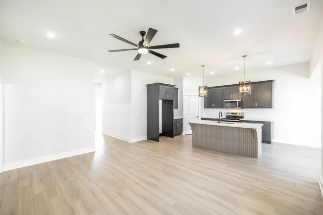 a large kitchen with a refrigerator a stove top oven a sink and dishwasher with wooden floor