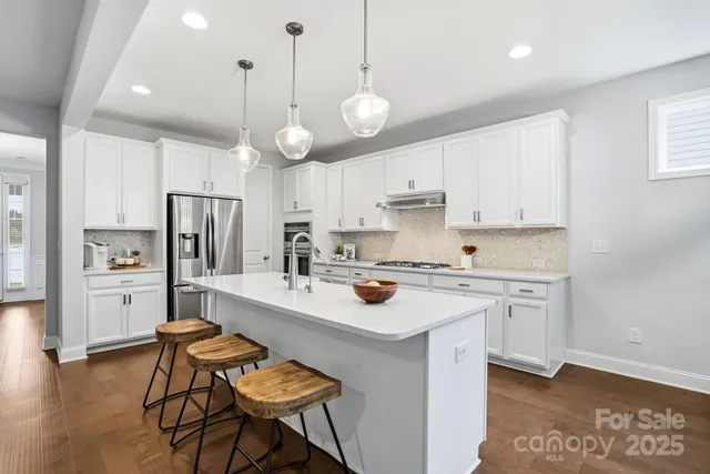 a kitchen with a center island white cabinets and stainless steel appliances