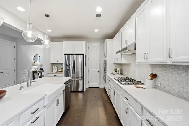 a kitchen with kitchen island stainless steel appliances a sink cabinets and wooden floor