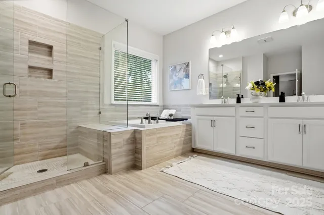a bathroom with a bathtub a double vanity sink and a mirror