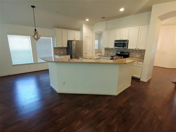 a kitchen with stainless steel appliances granite countertop a sink a microwave a refrigerator a stove a microwave and wooden floors
