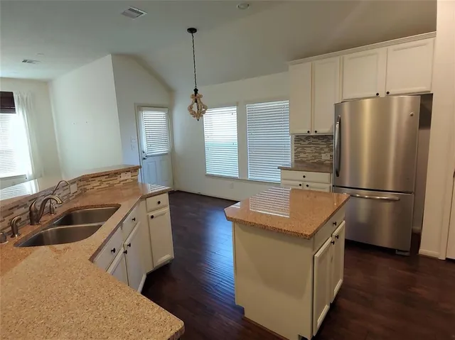 a kitchen with stainless steel appliances granite countertop a refrigerator a sink a stove and a wooden floors