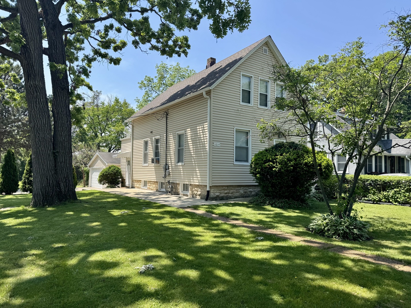 a backyard of a house with table and chairs plants and large tree