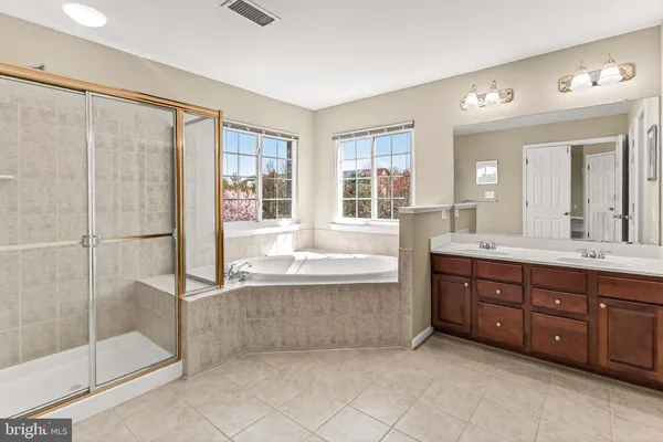 a spacious bathroom with a tub sink shower and mirror