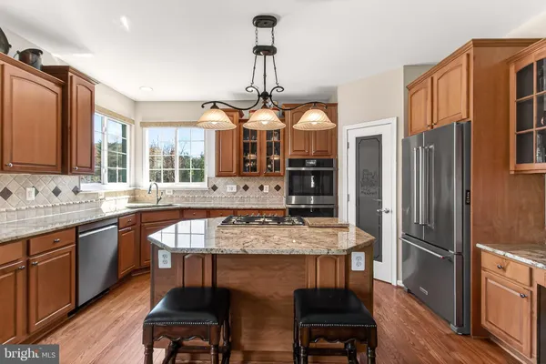 a kitchen with stainless steel appliances granite countertop a stove a sink dishwasher a refrigerator a oven a kitchen island with a dining table and chairs
