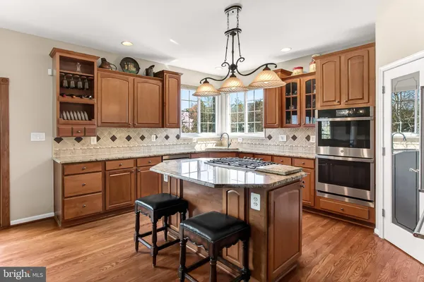 a kitchen with stainless steel appliances granite countertop a stove a sink dishwasher and a refrigerator with wooden floor