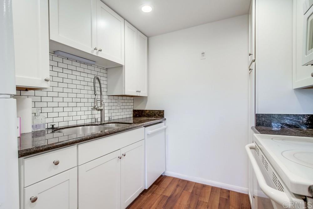 12643 Robison Boulevard, Unit 213 Poway, CA 92064 - Photo 21 of 49 a kitchen with granite countertop white cabinets and white appliances