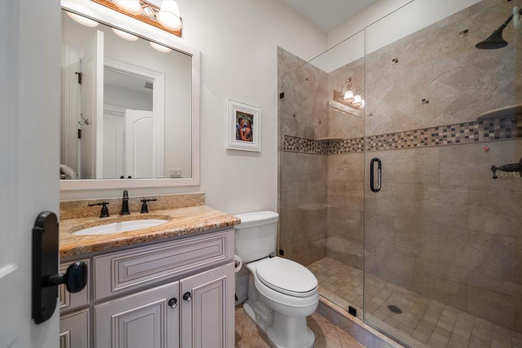 10930 Spring Street Largo, FL 33774 - Photo 40 of 100 a bathroom with a granite countertop sink a toilet and shower