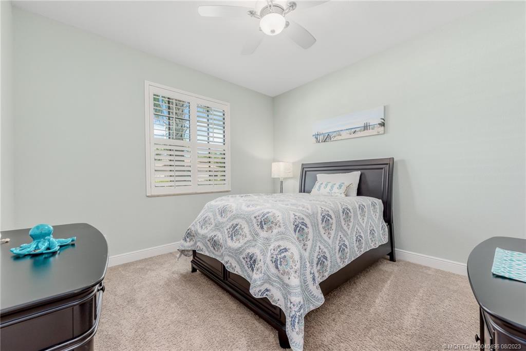 5891 Southeast Entry Court Stuart, FL 34997 - Photo 12 of 29 a bedroom with a bed and a chandelier