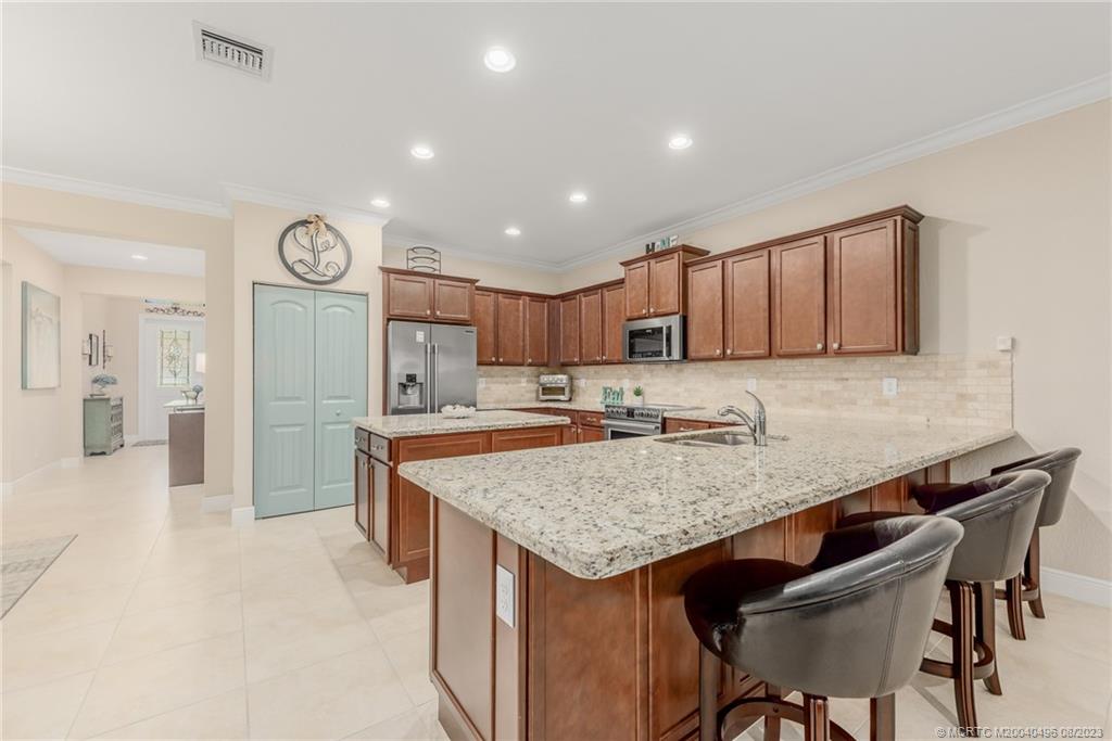 5891 Southeast Entry Court Stuart, FL 34997 - Photo 6 of 29 a kitchen with granite countertop a table chairs a sink and a refrigerator