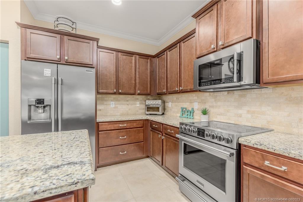 5891 Southeast Entry Court Stuart, FL 34997 - Photo 7 of 29 a kitchen with stainless steel appliances granite countertop a stove microwave and refrigerator