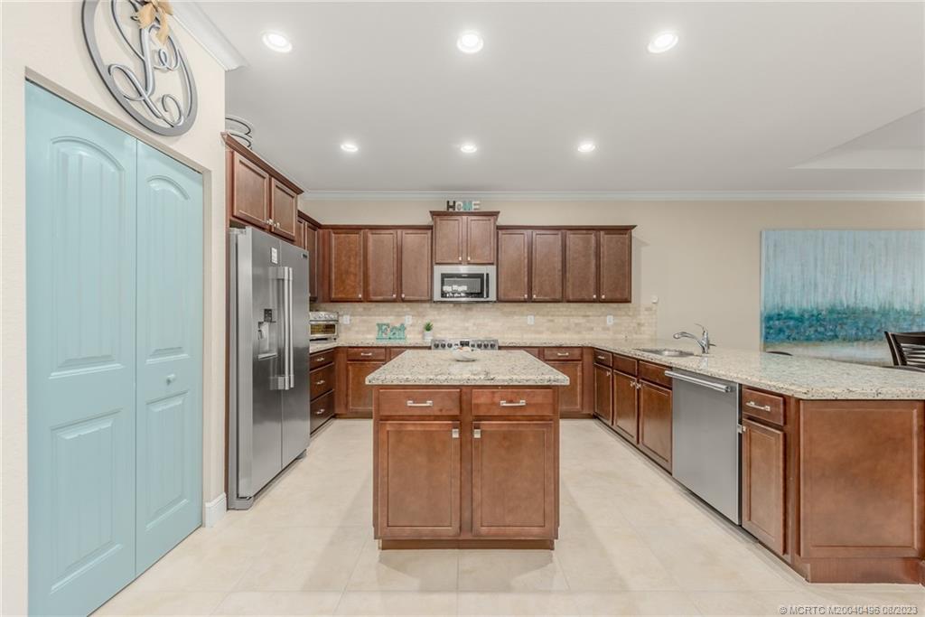 5891 Southeast Entry Court Stuart, FL 34997 - Photo 8 of 29 a large kitchen with stainless steel appliances granite countertop a stove a sink and a refrigerator with wooden floor