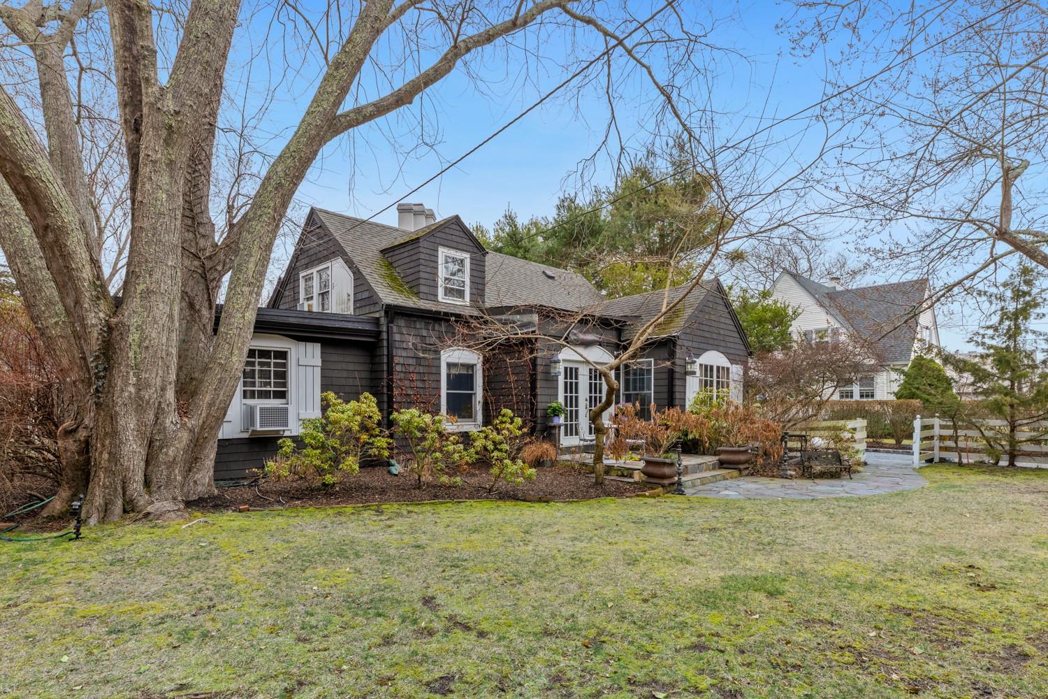 Shingle-style home featuring cooling unit, fence, a front lawn, a shingled roof, and a chimney