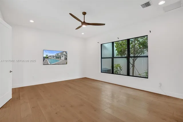 an empty room with a window and a ceiling fan