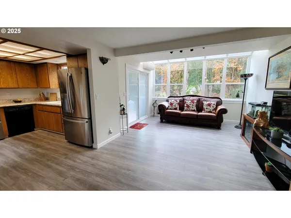 a kitchen with stainless steel appliances granite countertop a refrigerator a stove and a sink with wooden floor