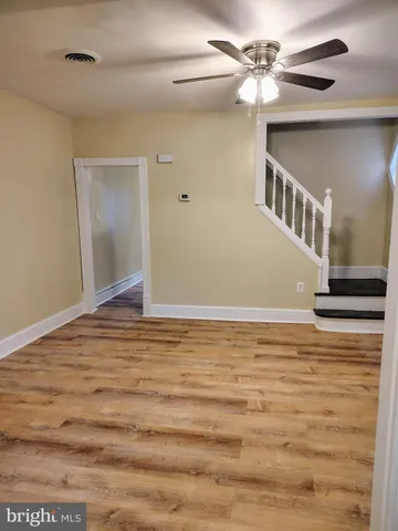 a view of a big room with wooden floor and ceiling fan