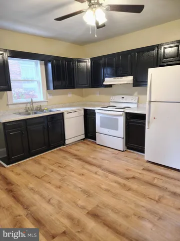 a kitchen with stainless steel appliances kitchen island granite countertop a refrigerator stove a sink and dishwasher with wooden floor