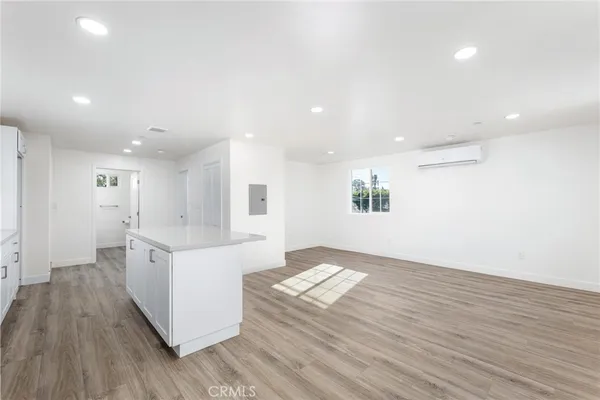 a large white kitchen with kitchen island a sink dishwasher a stove and a refrigerator with wooden floor