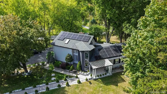 an aerial view of a house with swimming pool and large trees