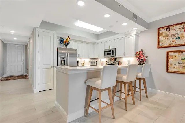 a dining room with stainless steel appliances kitchen island granite countertop a dining table chairs and a refrigerator