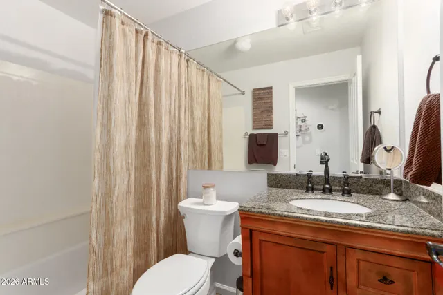 a bathroom with a granite countertop sink a toilet and a mirror