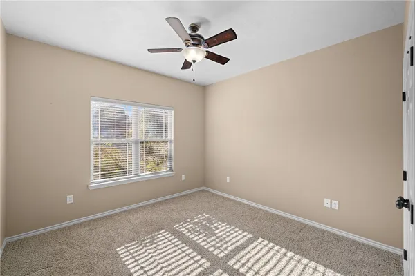 a view of an empty room with windows and ceiling fan