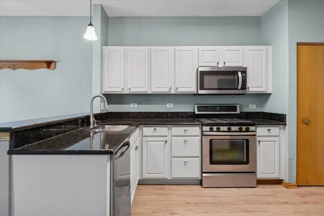 a kitchen with stainless steel appliances granite countertop a sink a stove a microwave and wooden cabinets