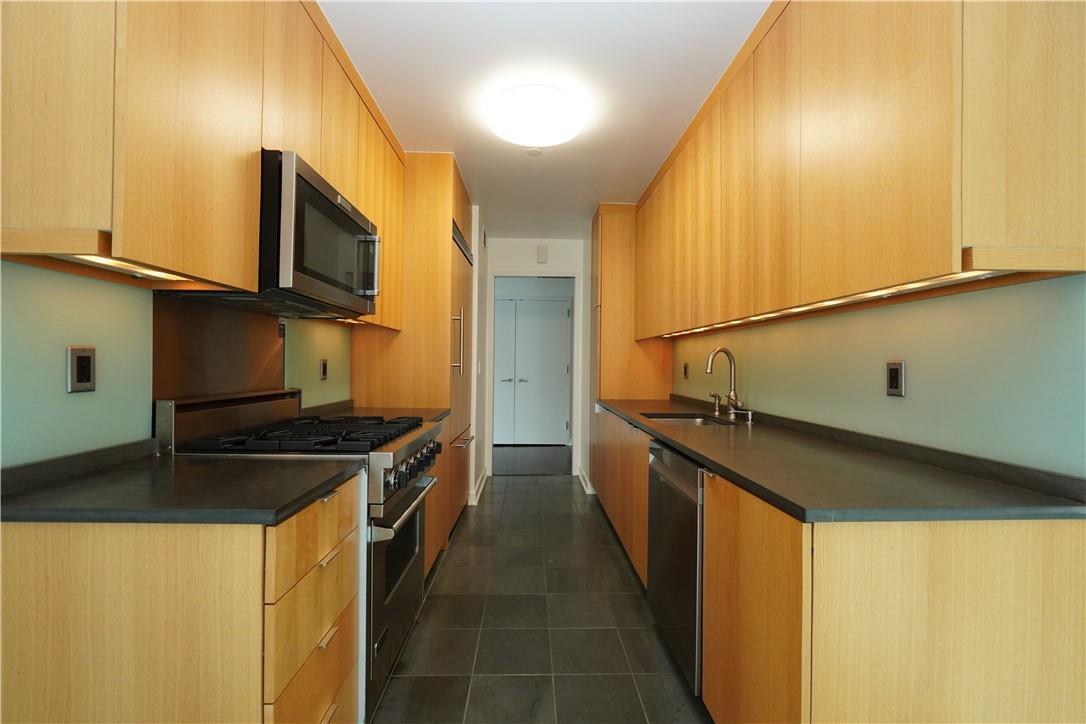 207 East 57th Street, Unit 21B Manhattan, NY 10022 - Photo 4 of 12 a kitchen with stainless steel appliances granite countertop a stove a sink and a microwave