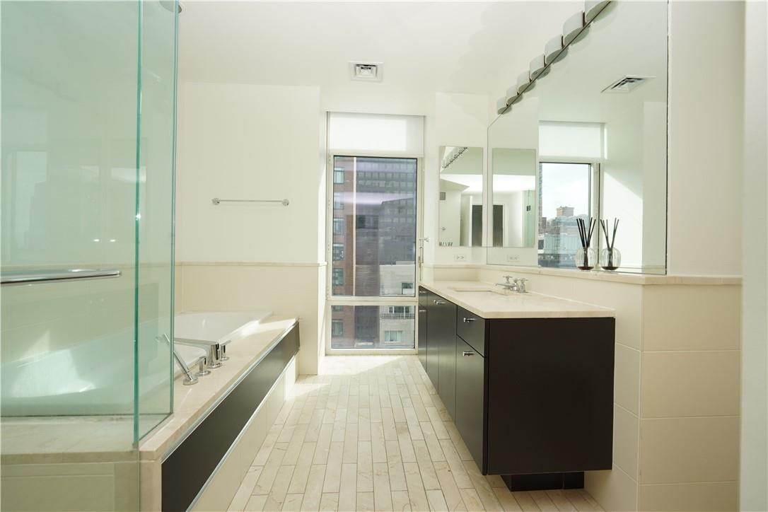 207 East 57th Street, Unit 21B Manhattan, NY 10022 - Photo 7 of 12 a bathroom with a sink a mirror and a bathtub