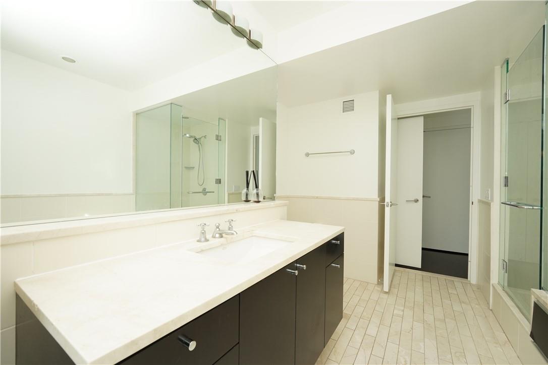 207 East 57th Street, Unit 21B Manhattan, NY 10022 - Photo 8 of 12 a bathroom with a sink a mirror and a shower