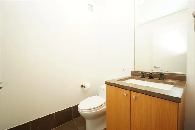 a bathroom with a granite countertop sink a toilet and mirror