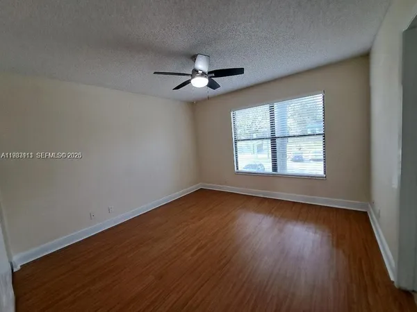an empty room with wooden floor ceiling fan and windows