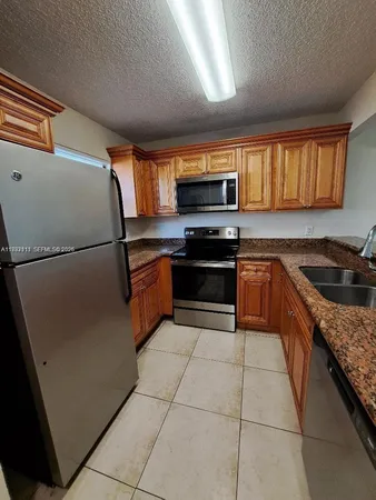 a kitchen with stainless steel appliances granite countertop a sink and a refrigerator