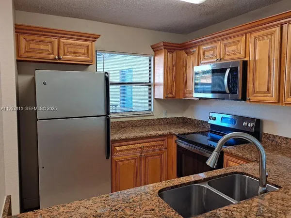 a kitchen with stainless steel appliances granite countertop a refrigerator sink and cabinets