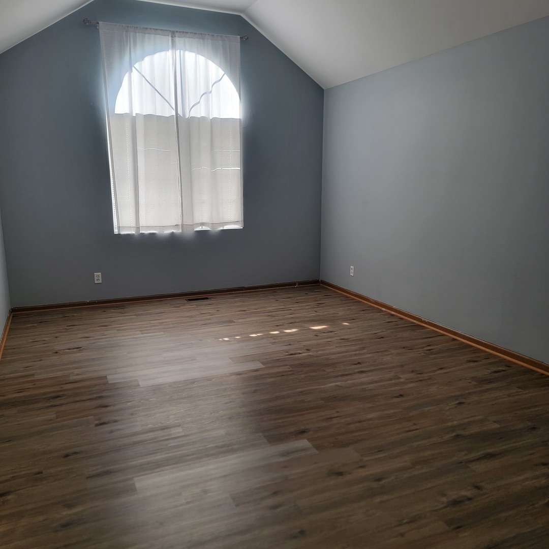 1540 Hickory Road, Unit 1540 Woodstock, IL 60098 - Photo 7 of 14 an empty room with wooden floor and windows