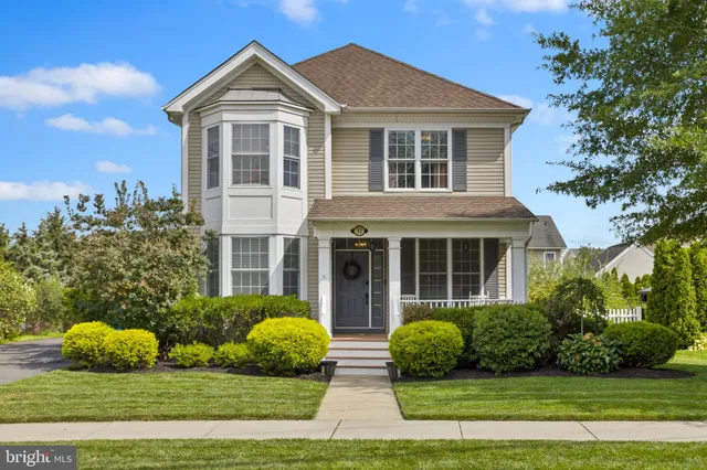 a view of a brick house with plants and large trees