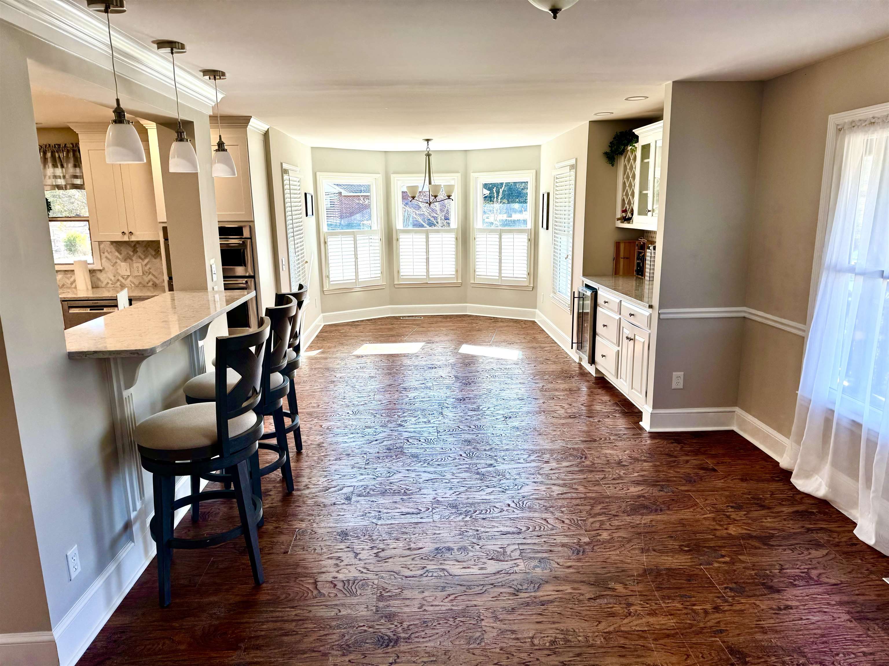 94 John Green Lane Georgetown, SC 29440 - Photo 10 of 35 Kitchen featuring a breakfast bar area, dark wood-type flooring, pendant lighting, light stone countertops, and glass insert cabinets