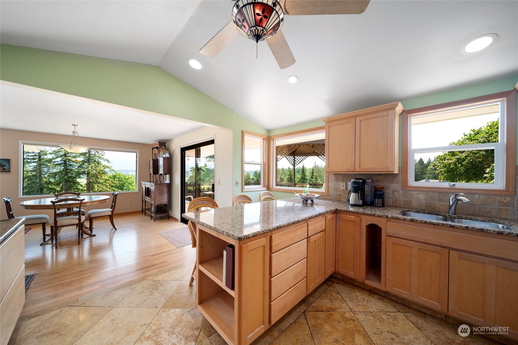 13622 Trumpeter Lane Mount Vernon, WA 98273 - Photo 20 of 40 a open kitchen with stainless steel appliances granite countertop a sink dishwasher a stove a dining table and chairs with wooden floor