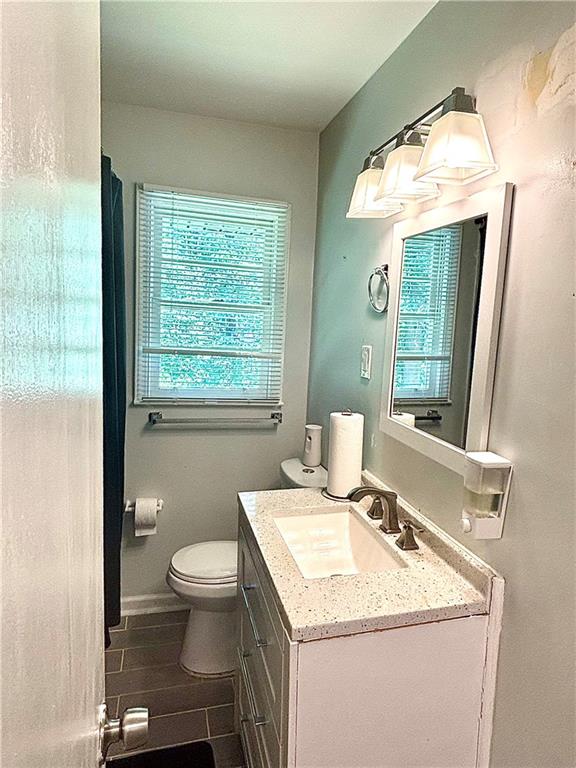 4030 Stonewall Tell Road Atlanta, GA 30349 - Photo 16 of 23 a bathroom with a granite countertop sink a toilet and a mirror