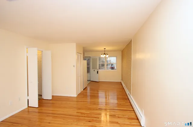 a view of a hallway with wooden floor and a bathroom