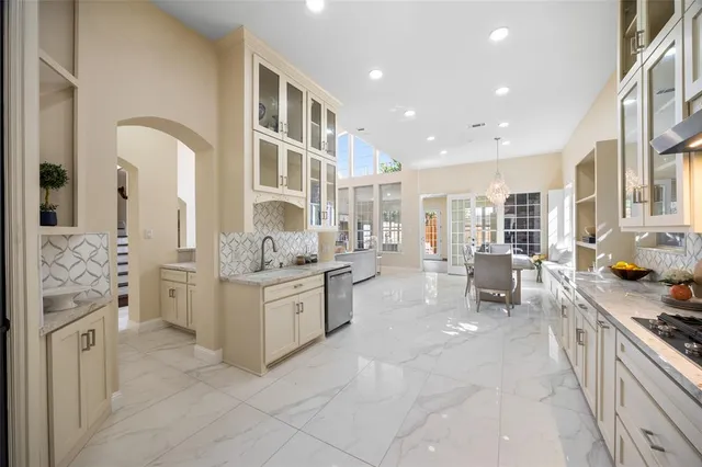 a large white kitchen with stainless steel appliances granite countertop a stove and a sink