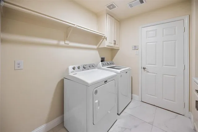 a utility room with cabinets washer and dryer