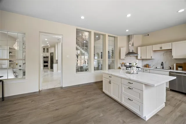 a large white kitchen with kitchen island white cabinets and stainless steel appliances
