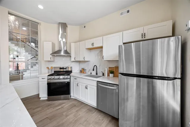 a kitchen with stainless steel appliances a refrigerator a stove a sink and white cabinets