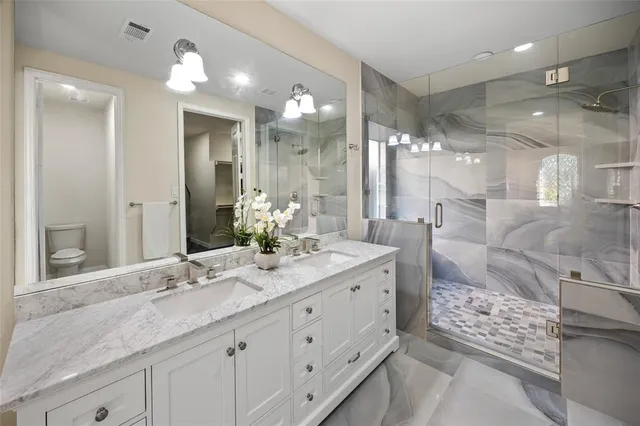a bathroom with a double vanity sink mirror and shower