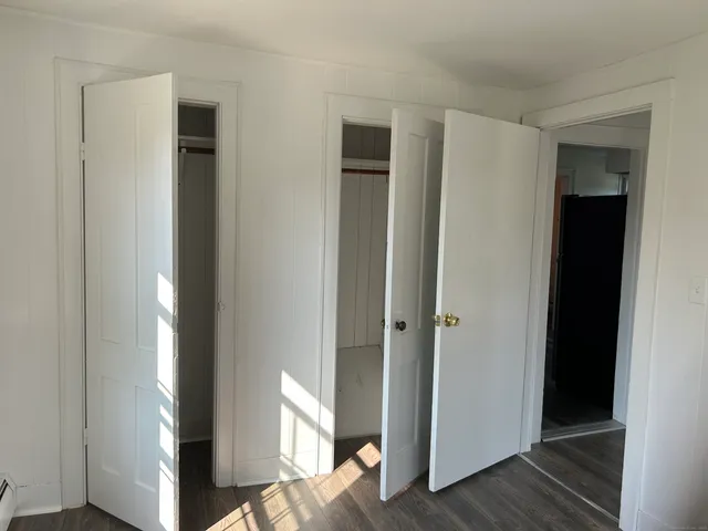 a view of a hallway with wooden floor and closet