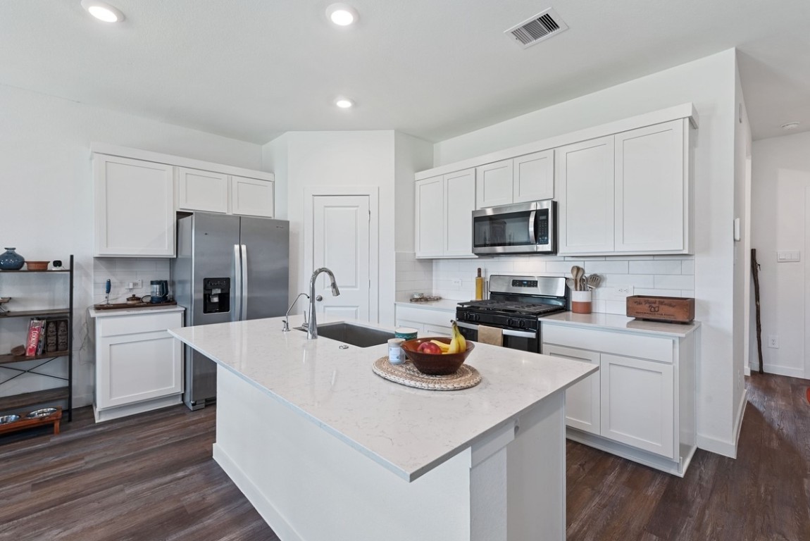 815 Devils Bridge Street Conroe, TX 77303 - Photo 4 of 25 a kitchen with a refrigerator a stove a microwave and wooden floor