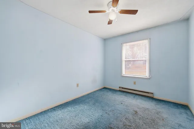an empty room with a window and a fan