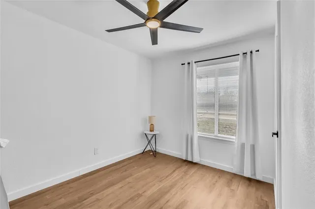 an empty room with wooden floor closet and windows