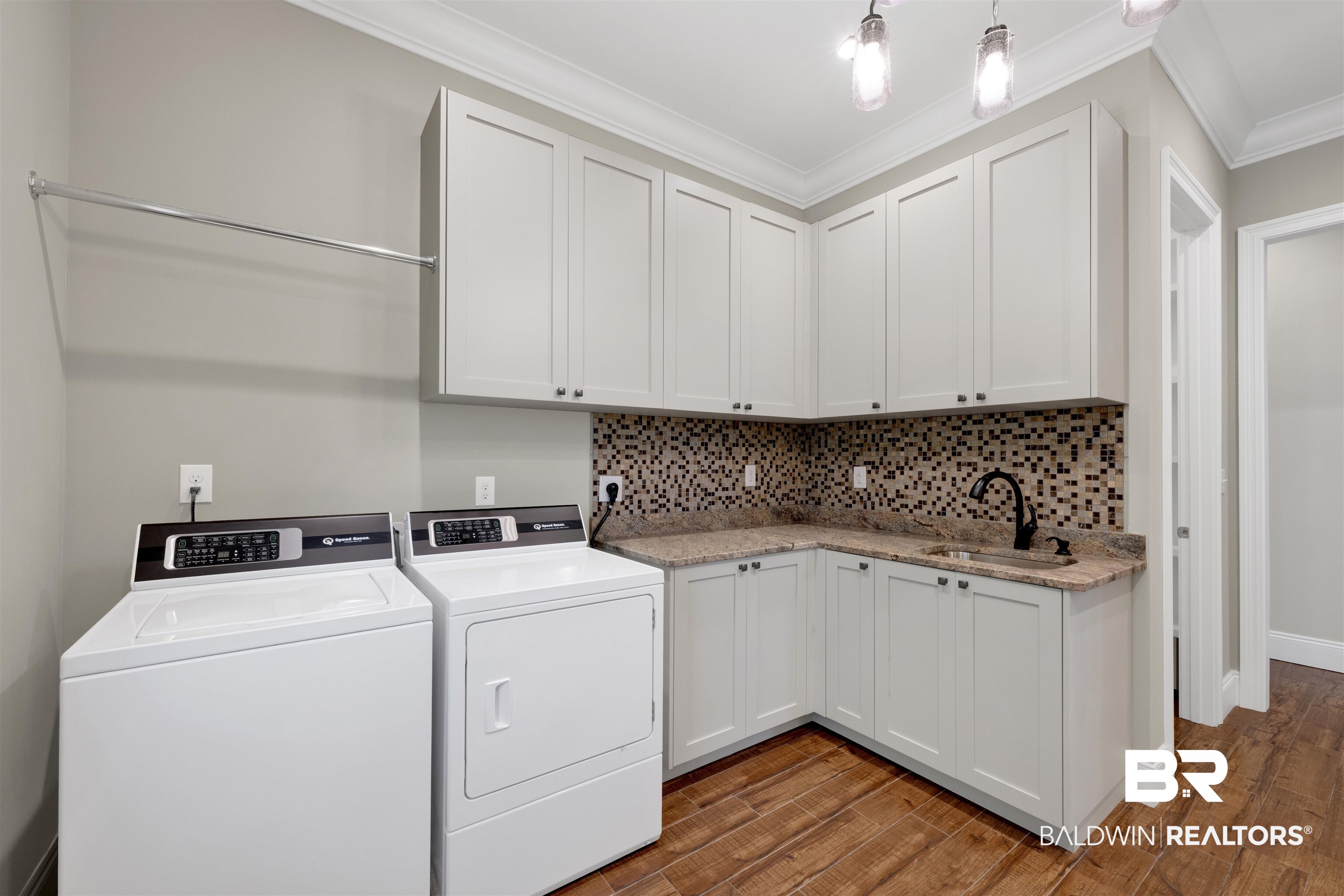 31729 River Road Orange Beach, AL 36561 - Photo 21 of 54 Laundry area featuring cabinet space, washing machine and dryer, dark wood-style floors, and ornamental molding
